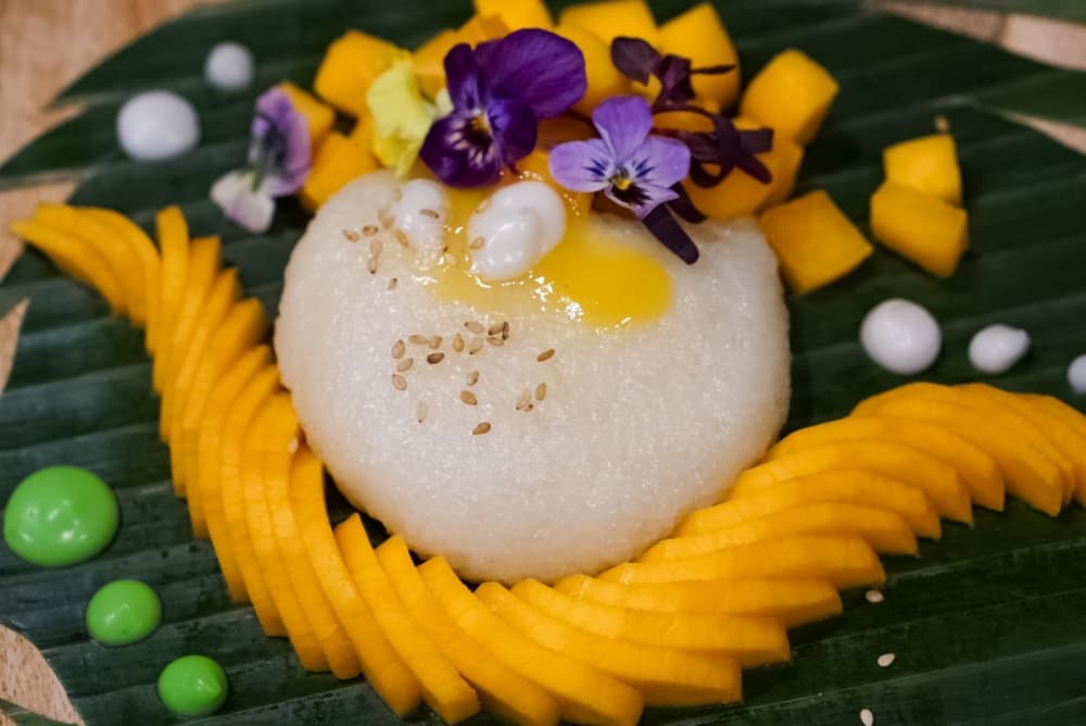A colorful food dish featureing mango and a flower