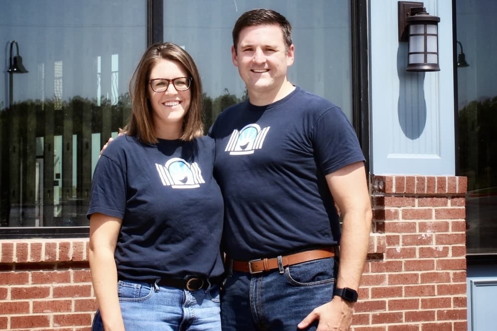 a man and woman pose for a photo at a storefront