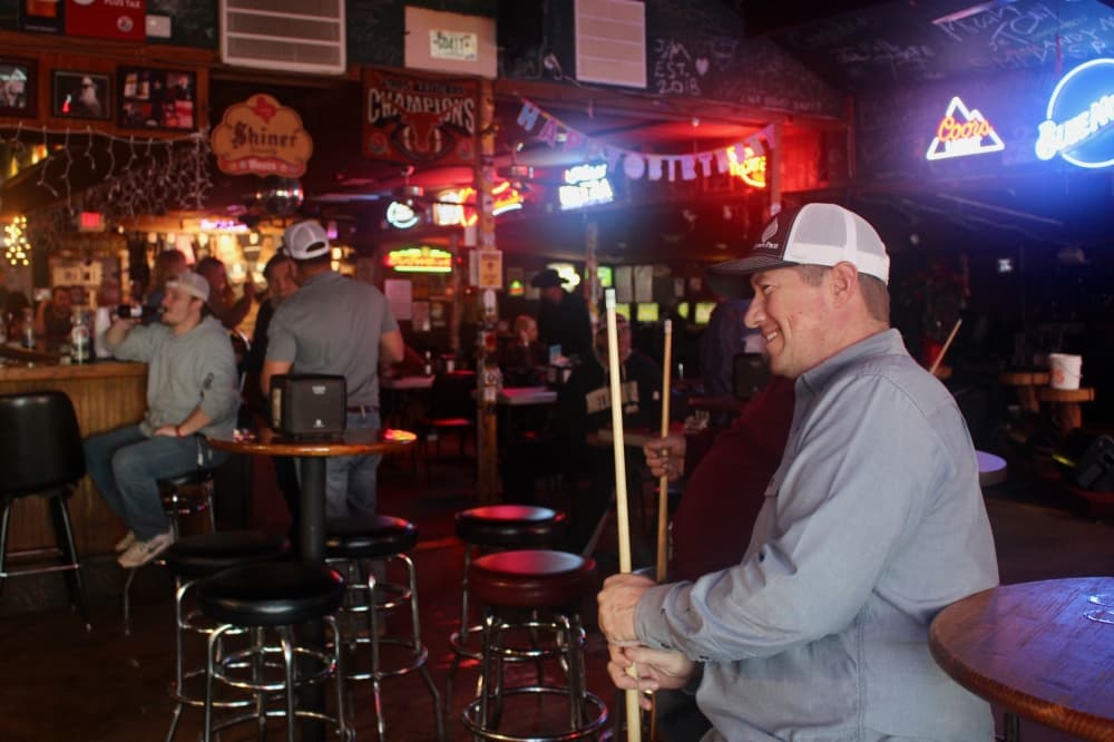 two people holding pool sticks look toward a performance