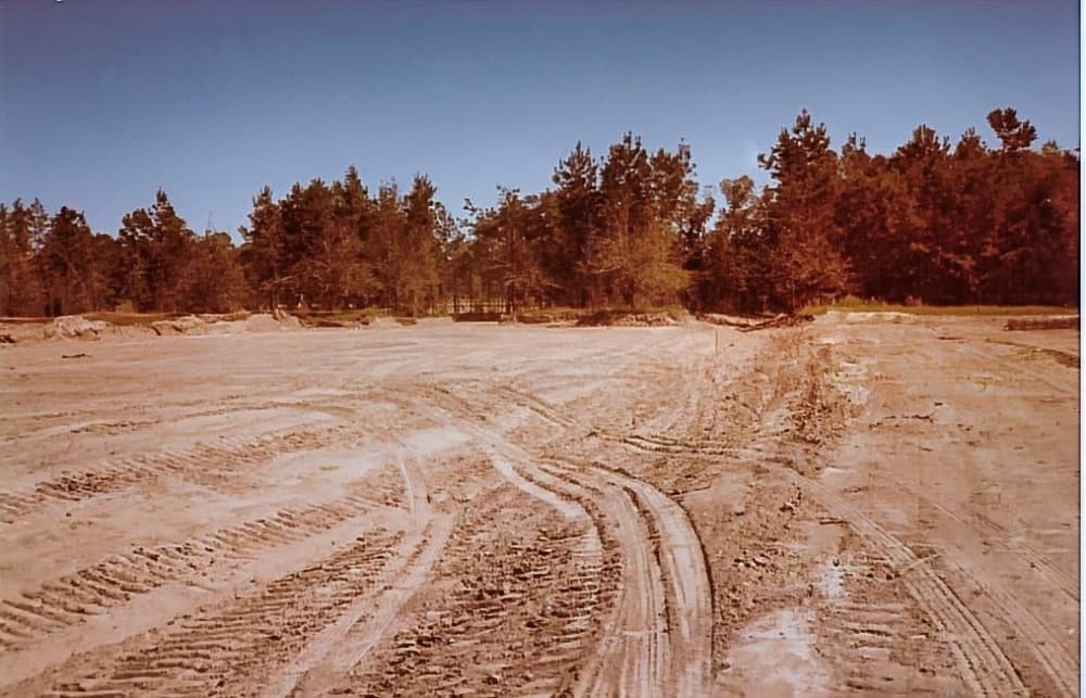 A vintage photo of an empty plot of land with vehicle tracks on it.