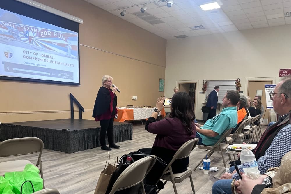 Tomball Mayor at the front of a room addressing a crowd