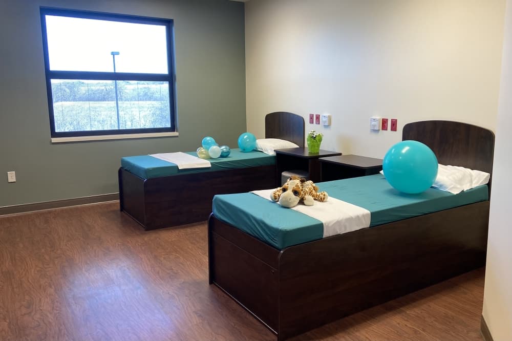 A room with two beds with teal and white covers