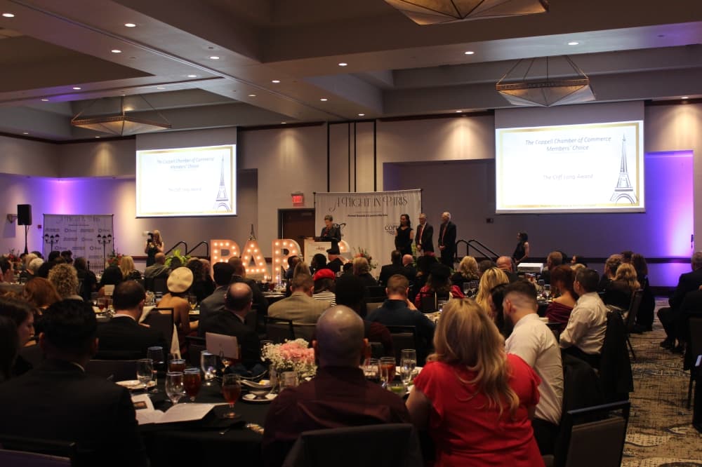 people gathered in a room watching someone speak at a podium