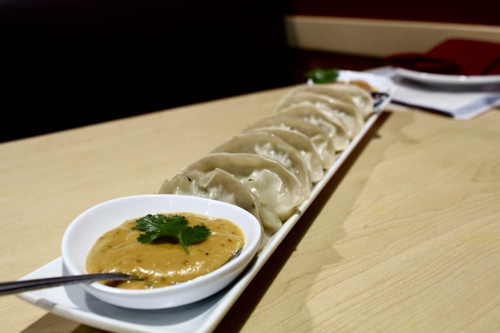 Steamed chicken dumplings with yellow sauce at front 