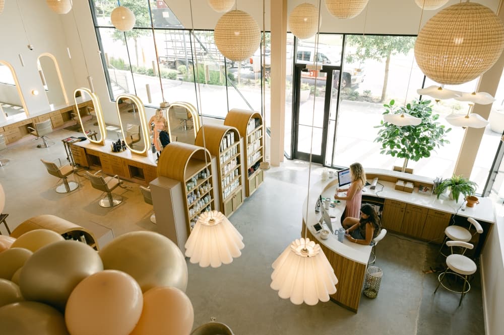 An aerial look at the inside of the salon shows various lighting options, salon chairs, the front desk and the front of the store filled with windows looking outside.