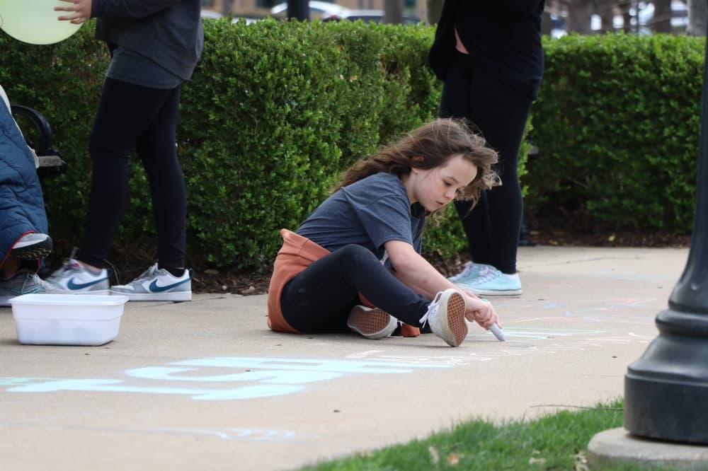 Girl drawing on a sidewalk with chalk. 