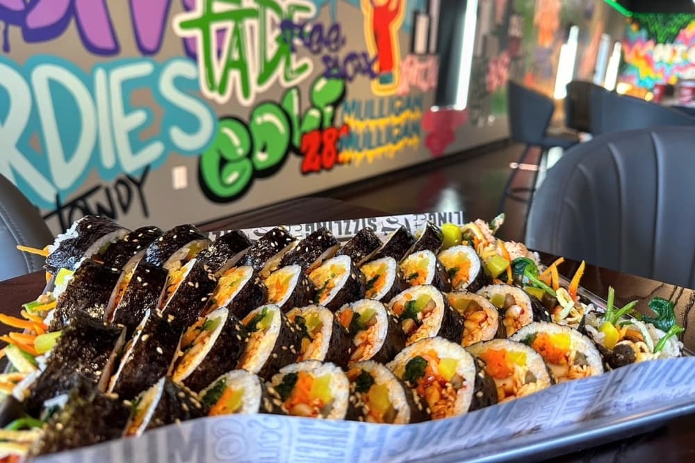 kimbaps on a tray with a mural on the wall behind it