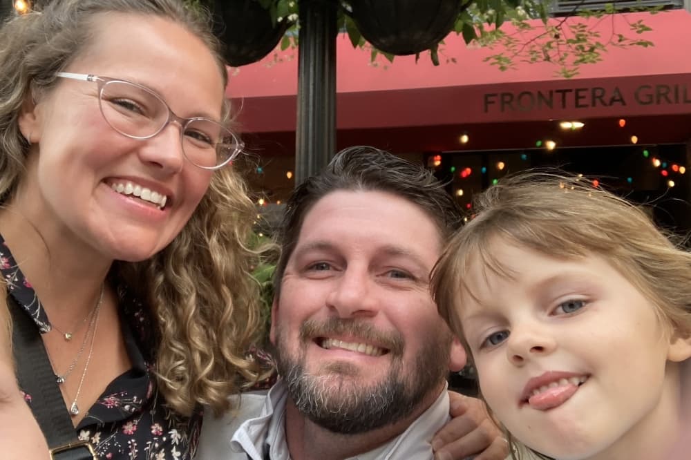 Camden Stuerzenberger is center in the photo, with his wife Aimee, to the left and young daughter, Phoebe.