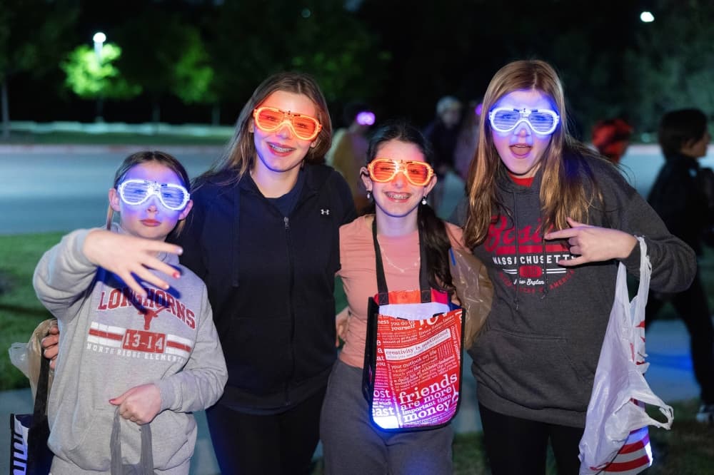Four girls wearing glow in the dark glasses.