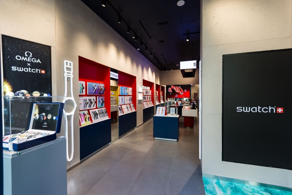 The interior is shown with signs reading "Swatch" and watches on display shelves in the background.