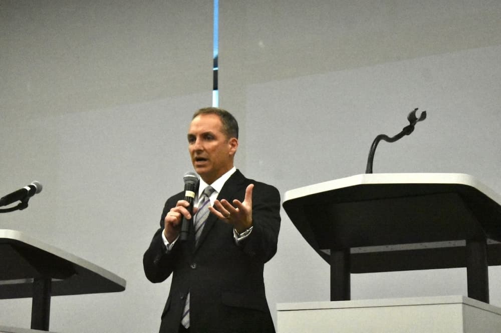 A man standing by a podium talks into a microphone