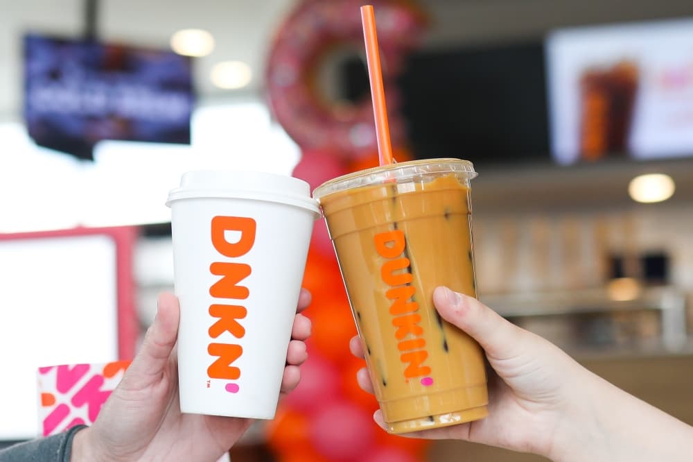Two coffees being held next to each other