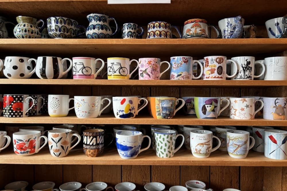 A shelf holds dozens of unique coffee mugs.
