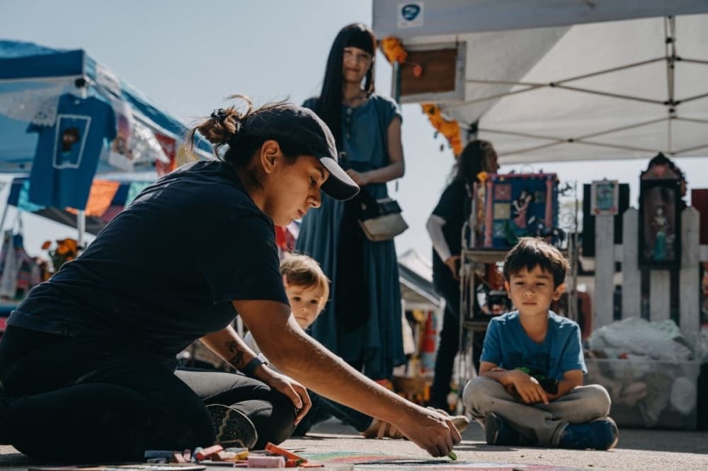 women draws in chalk as children look on