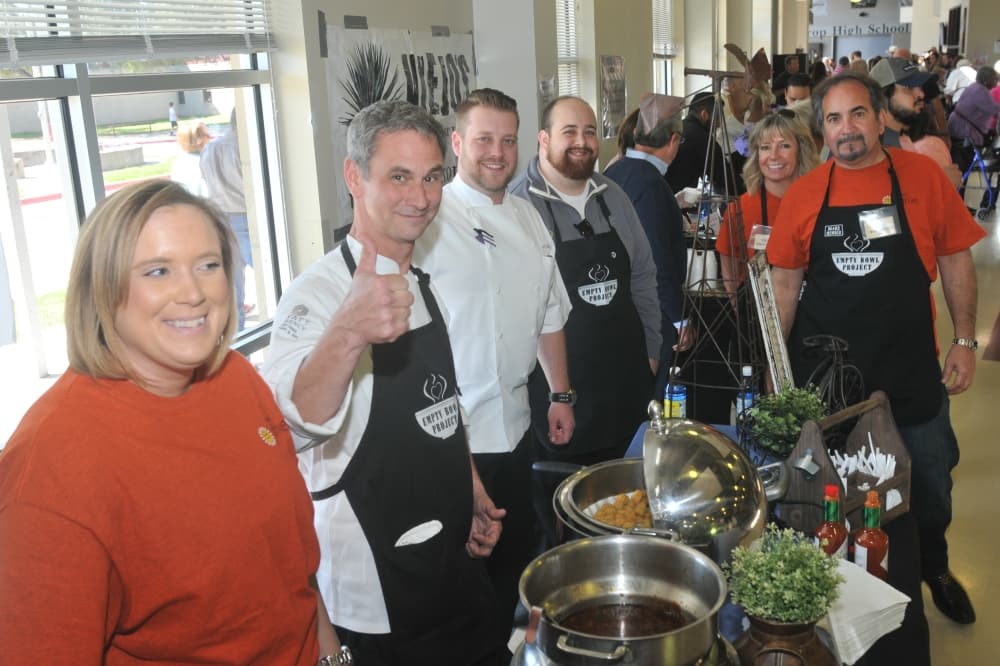 Several area chefs smile for the camera next to their cauldrons of soups.