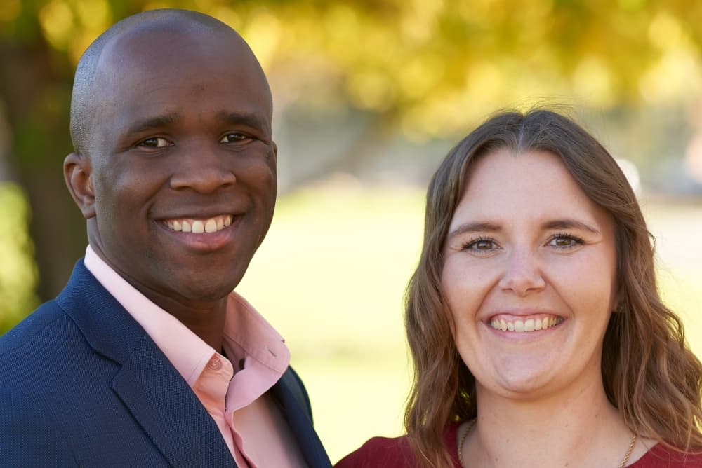 Husband and Wife, Imo and Maresha Eshiet stand side-by-side outside while smiling.