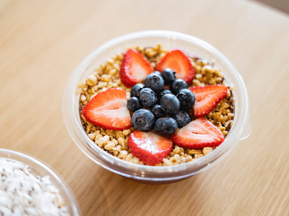 A smoothie bowl with fruit and granola on top.