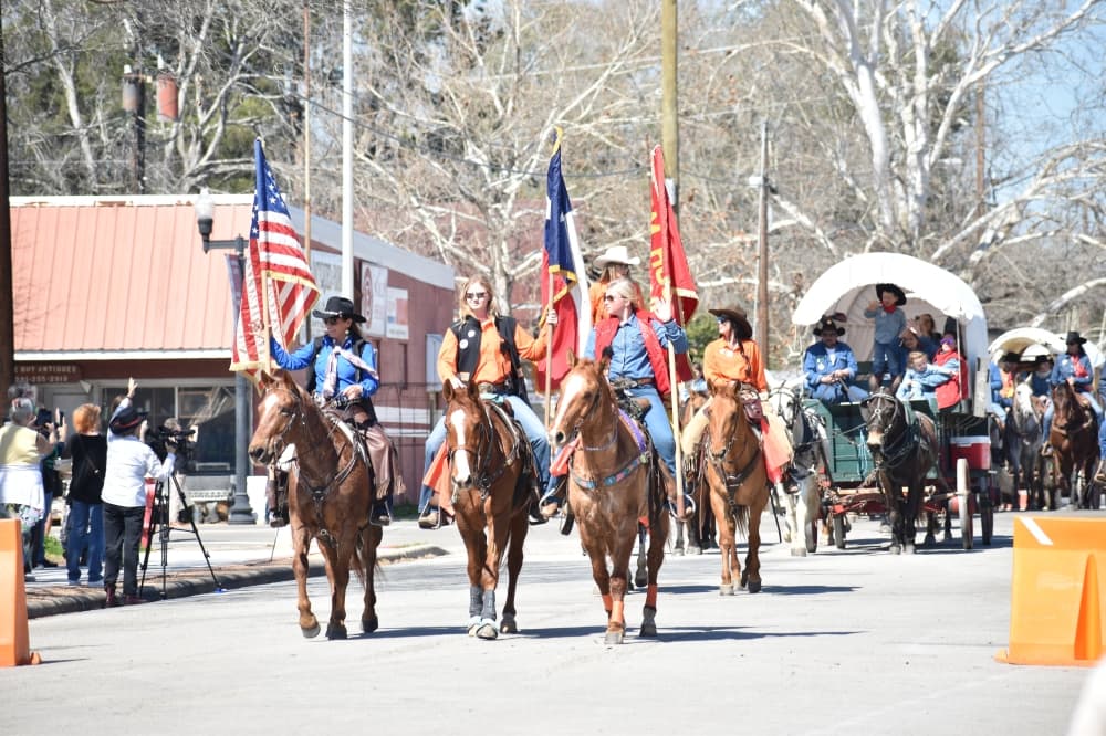 Three horseback riders carrying flags