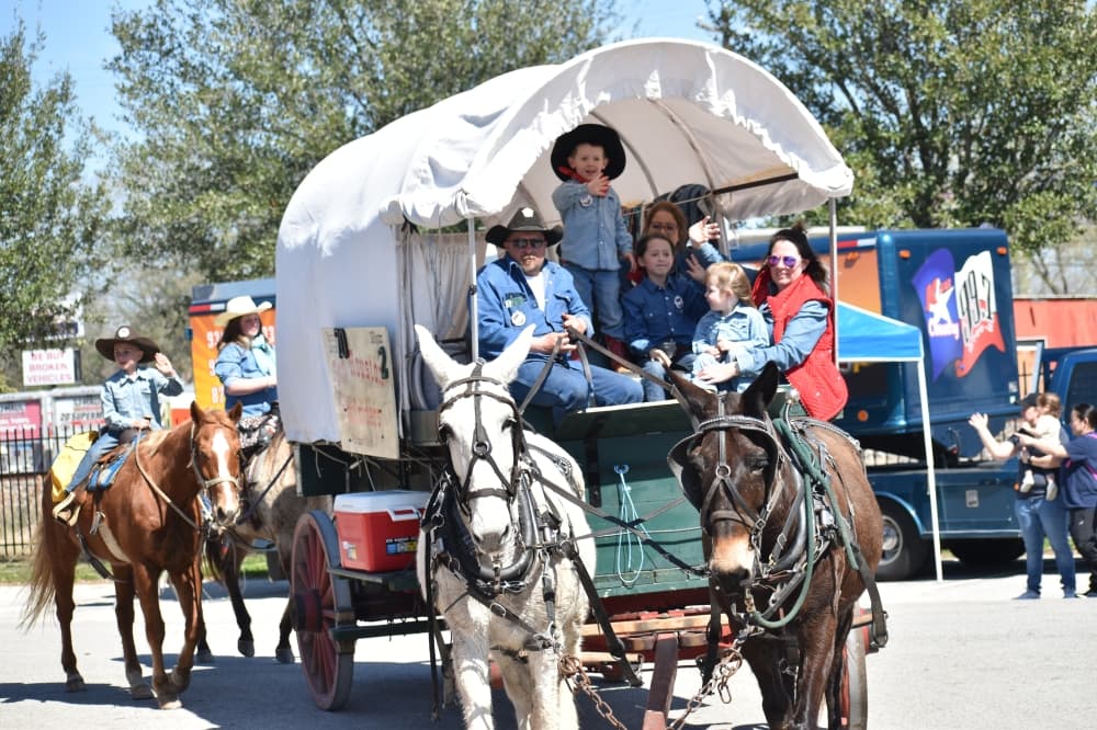 People on a horse-drawn wagon waving at the crowd