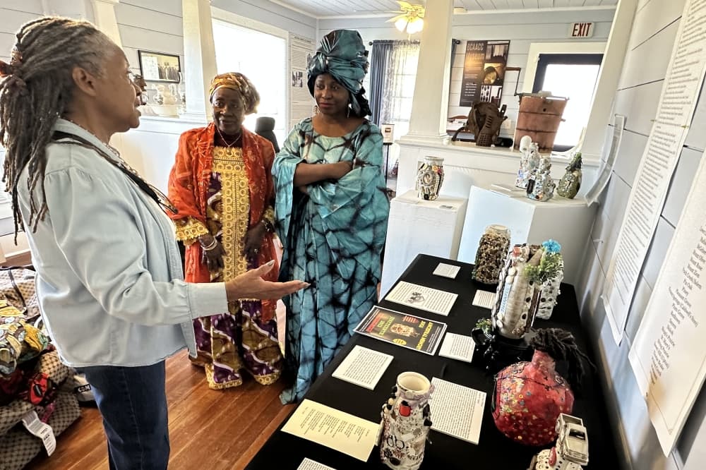 Two women from West Africa listen to another woman talk about African artifacts at the museum.