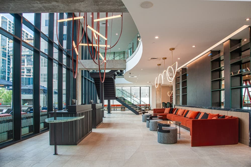 A look at the lobby with walls of windows and red couches.