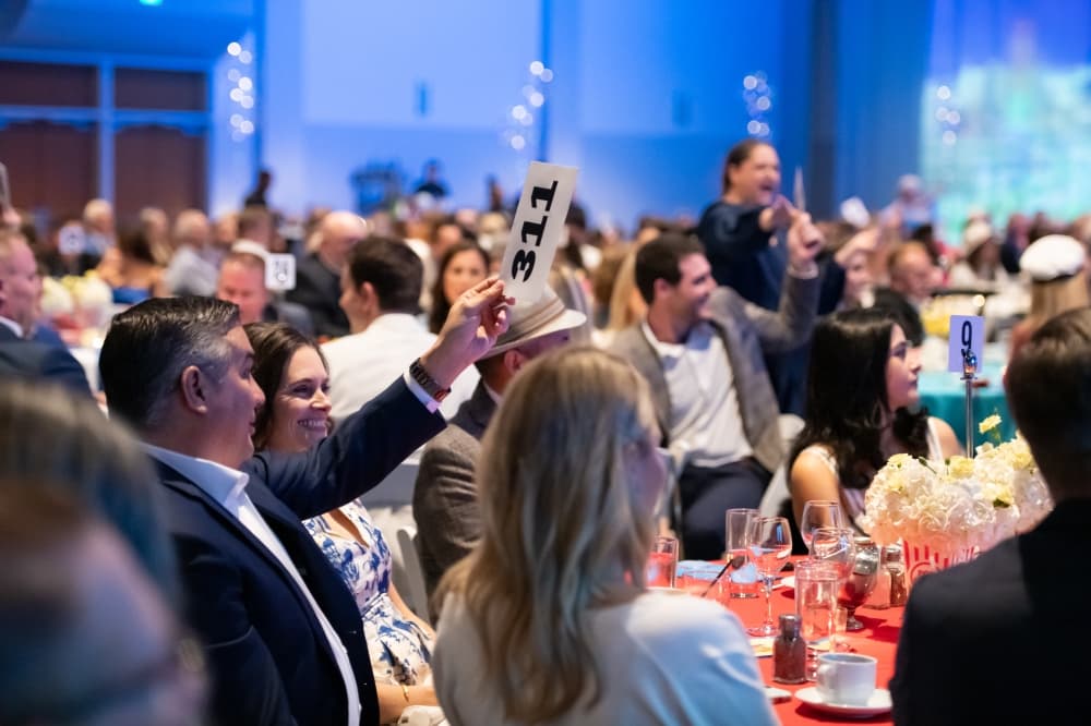 A man holds up a bid at a gala crowd.