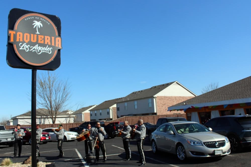 Mariachi band performing around Taqueria los Angeles sign