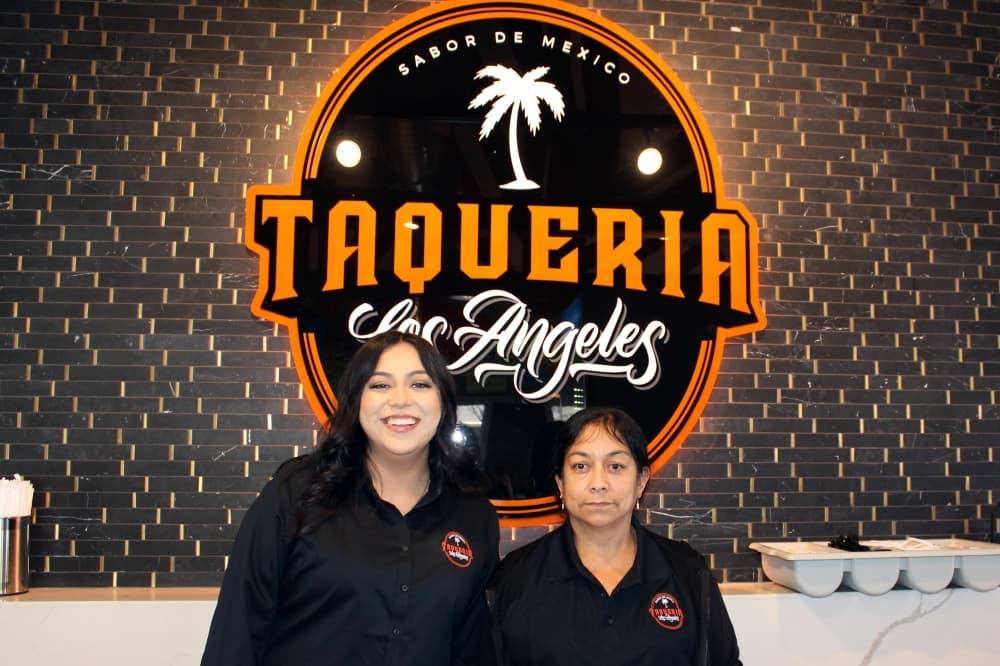 Two women standing in front of Taqueria Los Angeles sign 