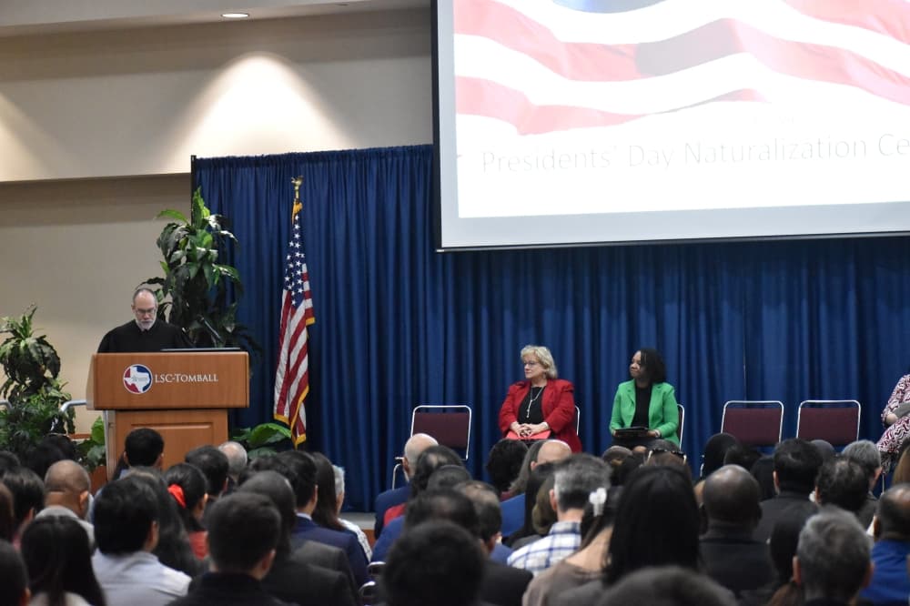 Judge at a podium in front of a room of people