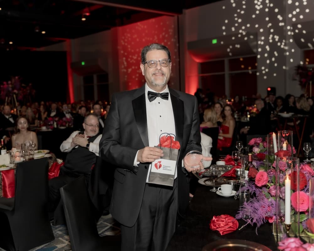 A man in a suit and bow tie holds an award