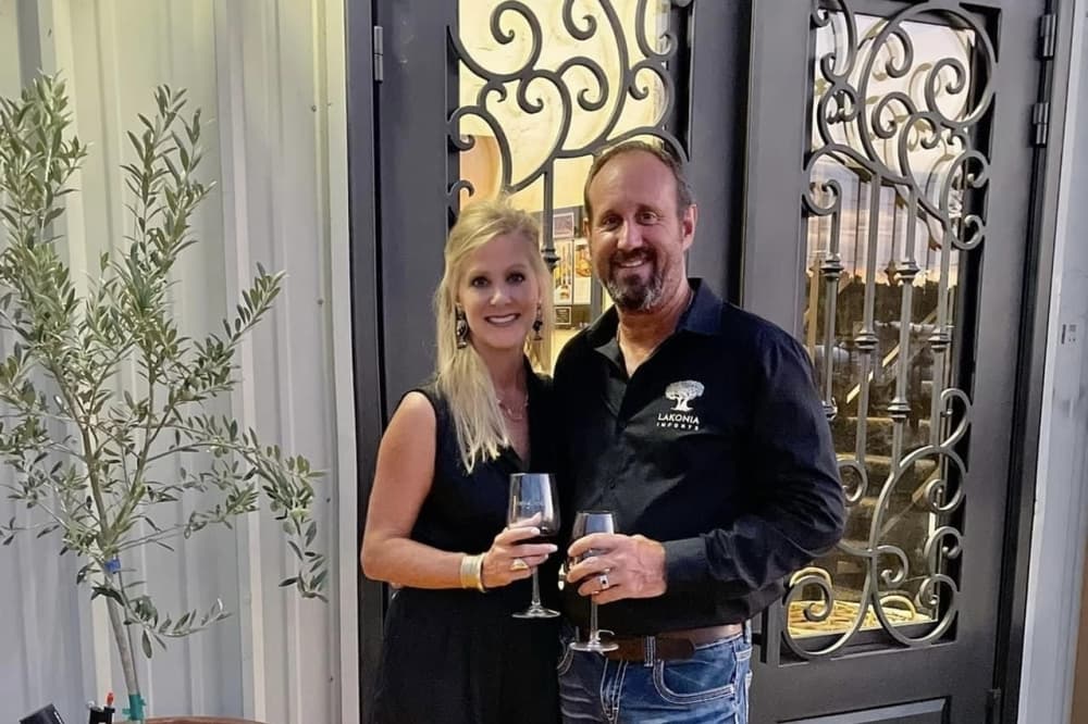 owners in front of door with wine glasses