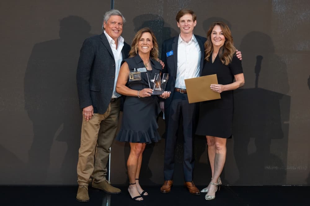 four people pose together with an award