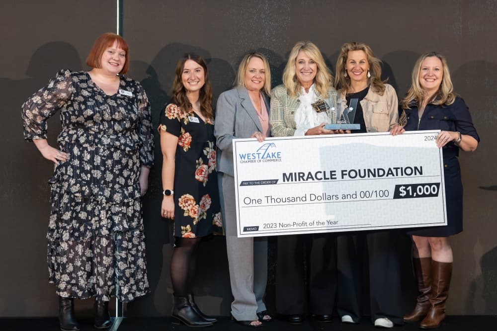 six people pose together with a large check