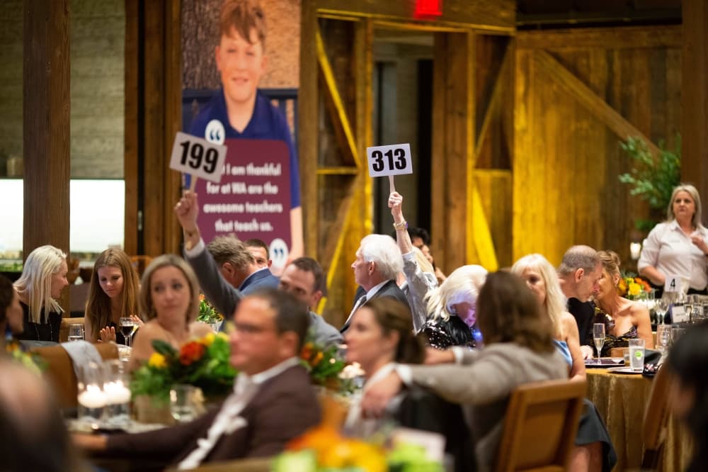 People holding up auction panels.