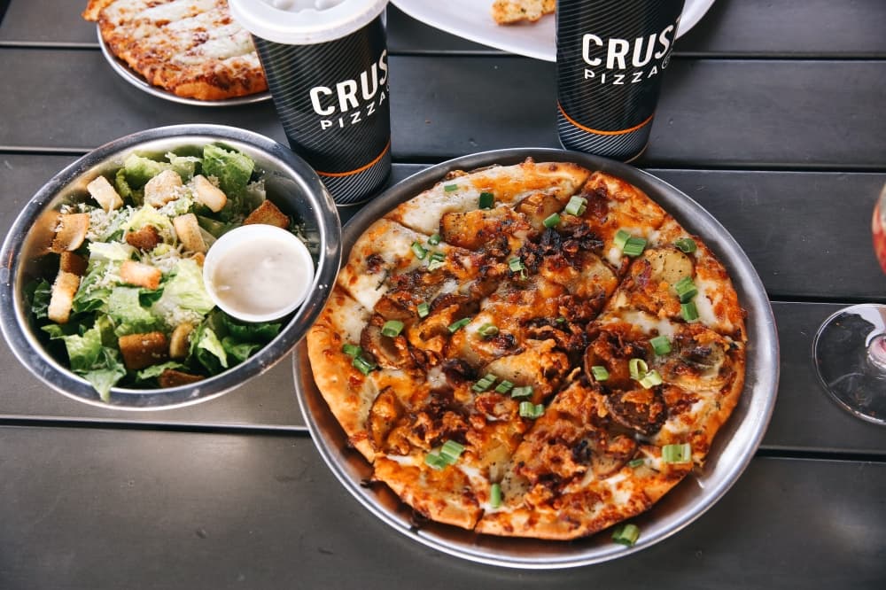Pizza next to a salad and two drinks