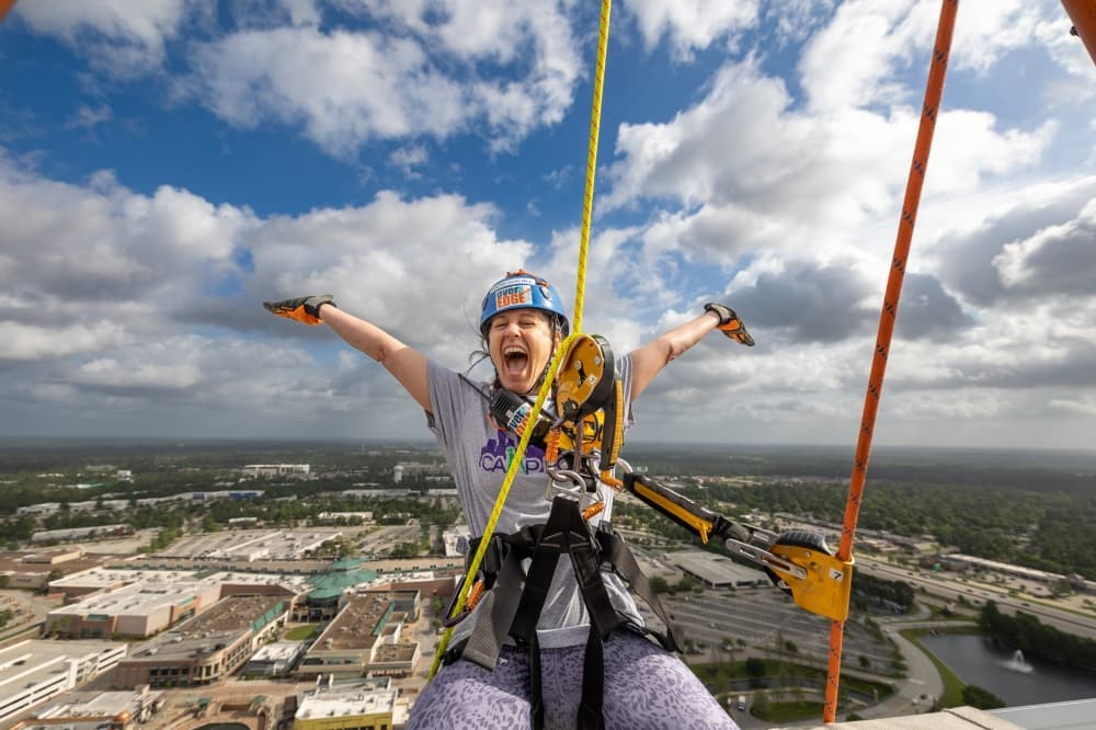 Person rappelling over the edge of building 