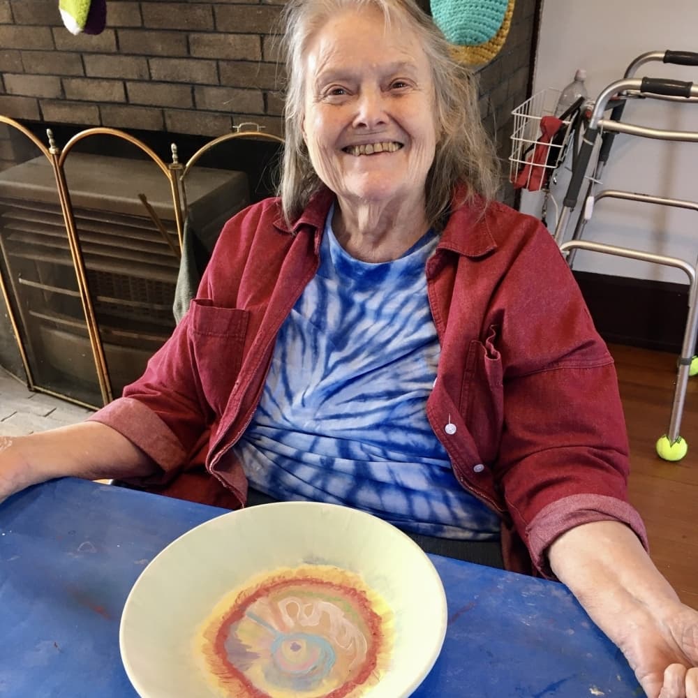 A women smiles while painting.