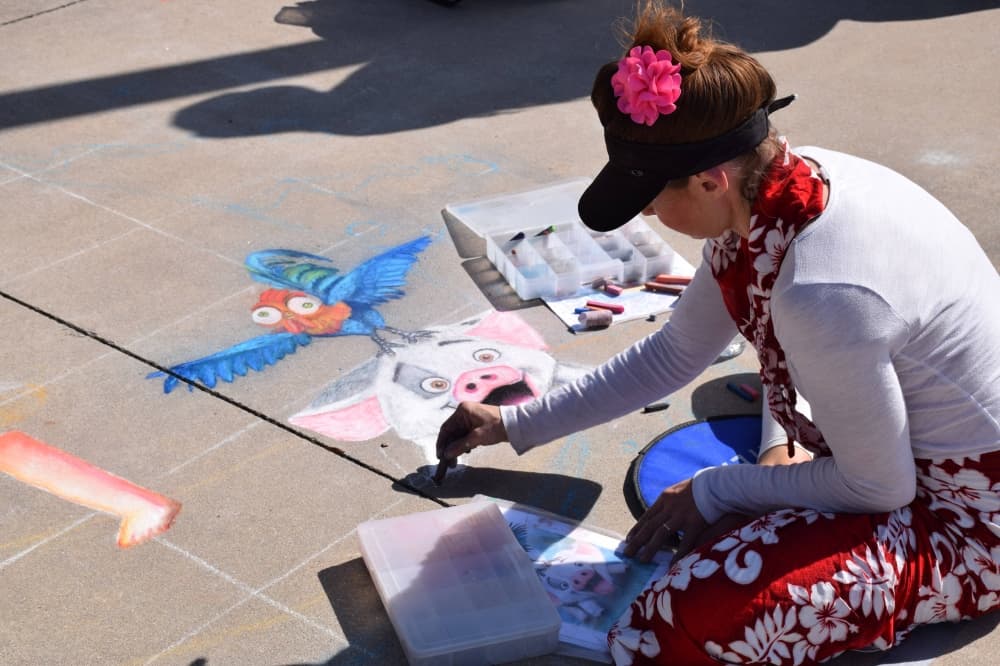 Woman drawing with chalk on a sidewalk. 