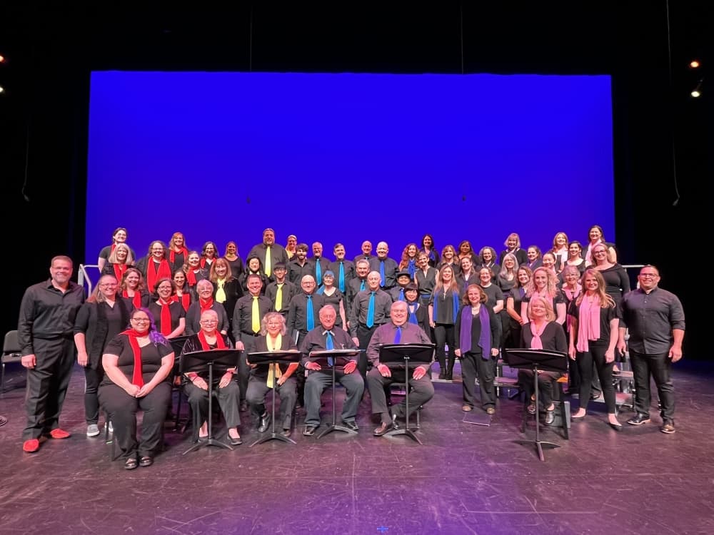 A group of people standing and sitting on a stage. 