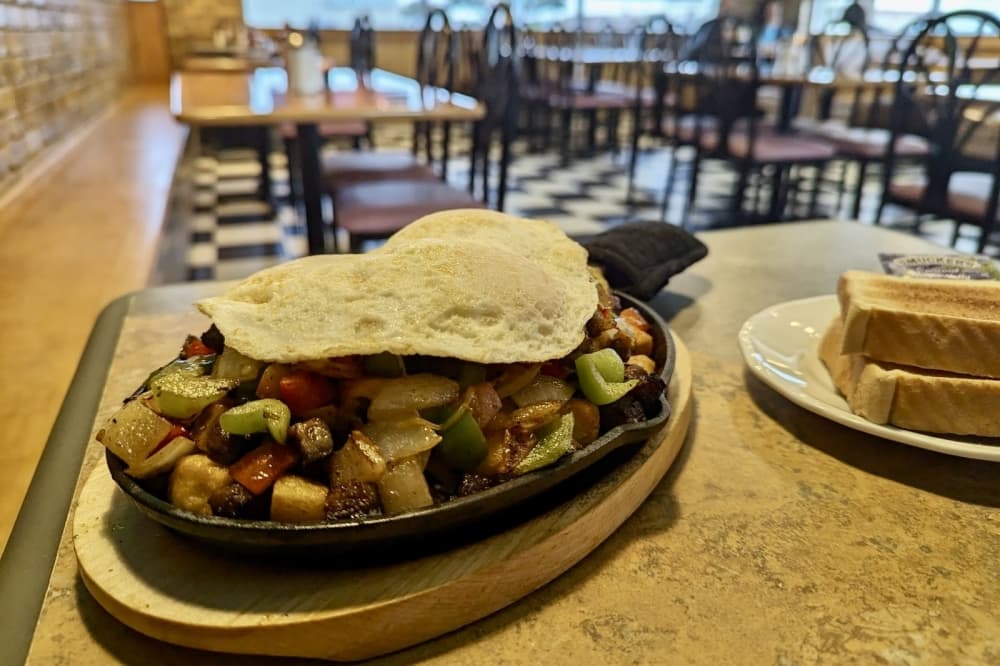 Popular dishes at Wisco Tx Cafe include the WiscoTex skillet, a heap of steak, tomatoes red and green peppers, onions, and cheddar cheese served on a bed of potatoes and topped with three eggs. (Jonathan Perriello/Community Impact)