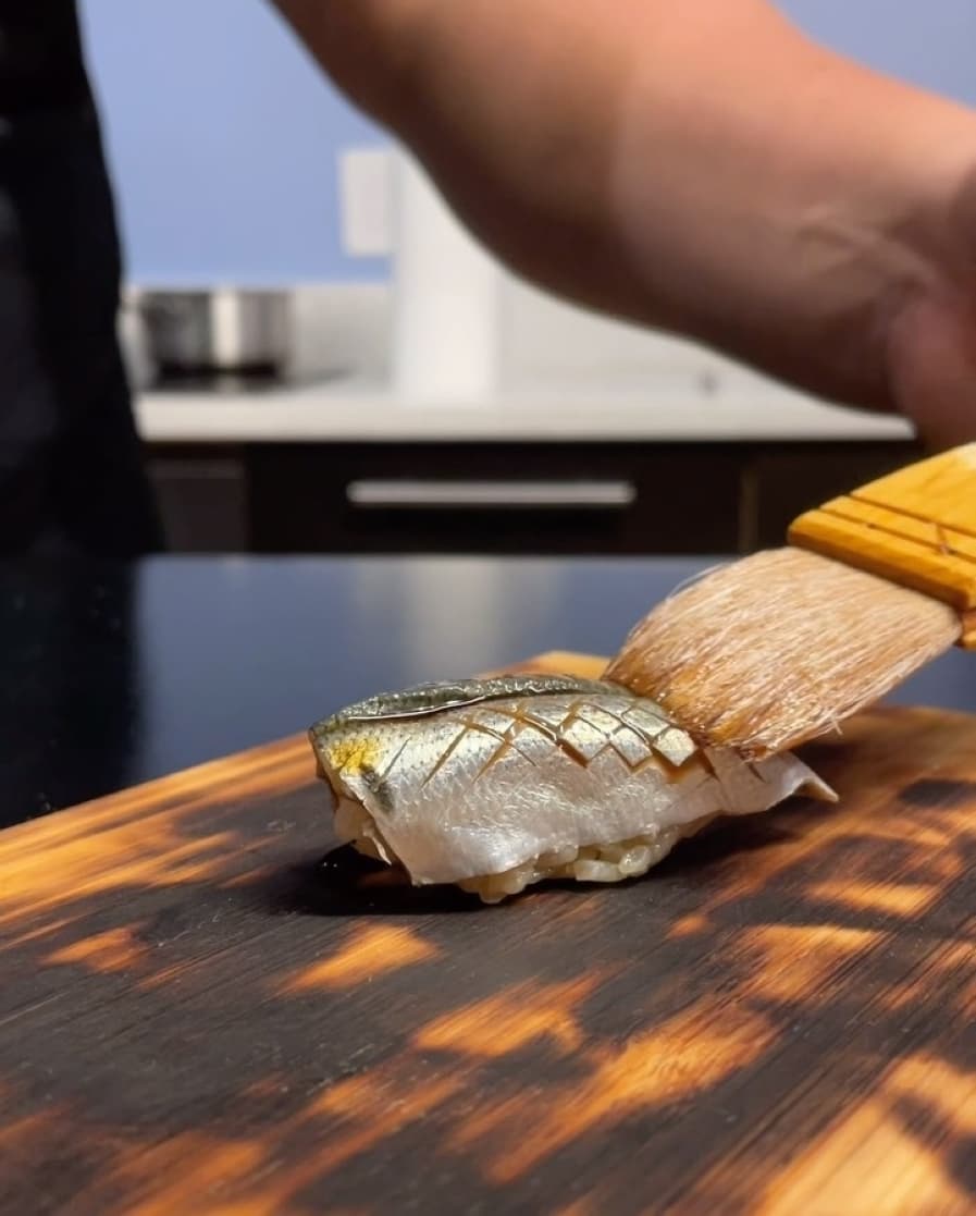 A piece of fish is shown being brushed with a glaze.