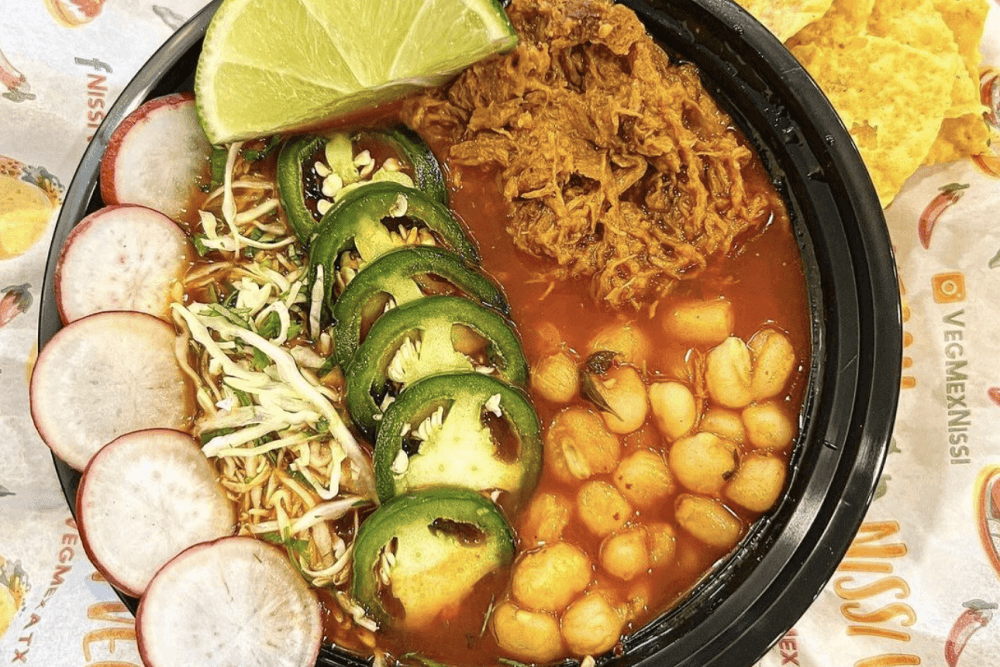 A bowl of soup with radish slices, jalapenos and more.