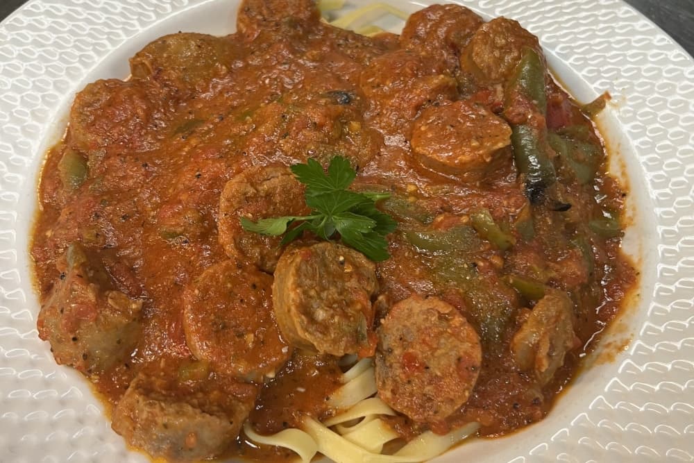 A pasta dish with red sauce and sausage is shown.