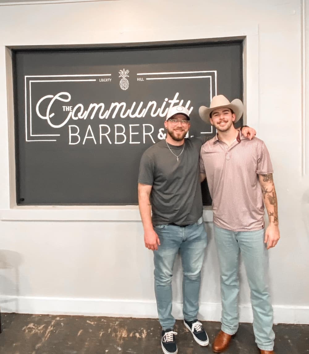  Anthony Kendig and Caeden Kieper in front of wall with business logo 