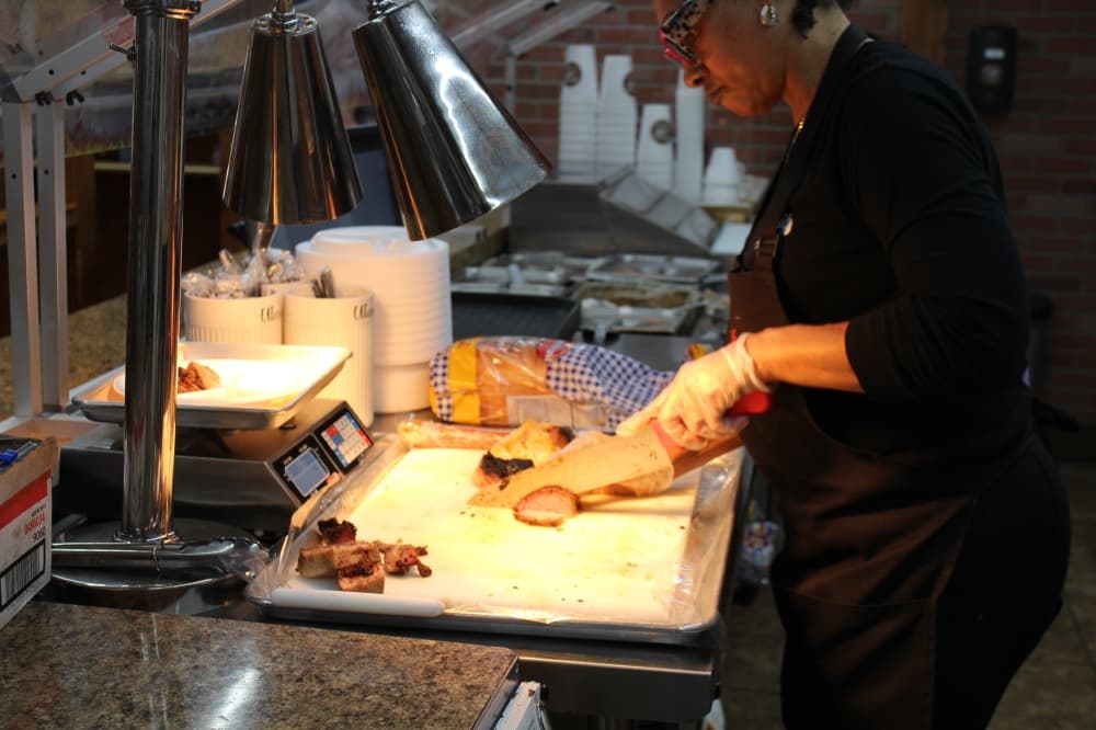 Katha Dickerson, general manager of The Big Bib BBQ in New Braunfels, slices brisket for lunch orders. (Sarah Hernandez/Community Impact)
