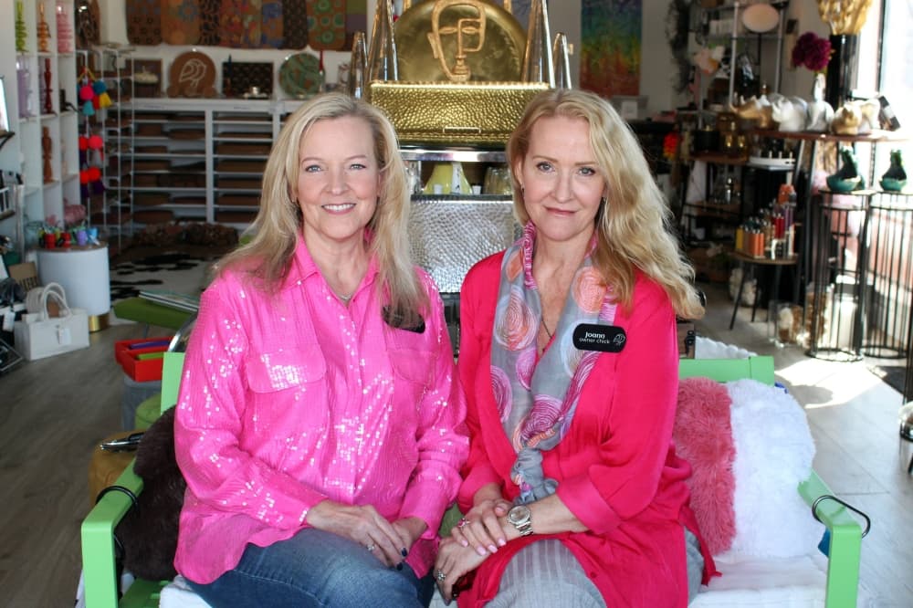 Two females sitting side by side in a store. 