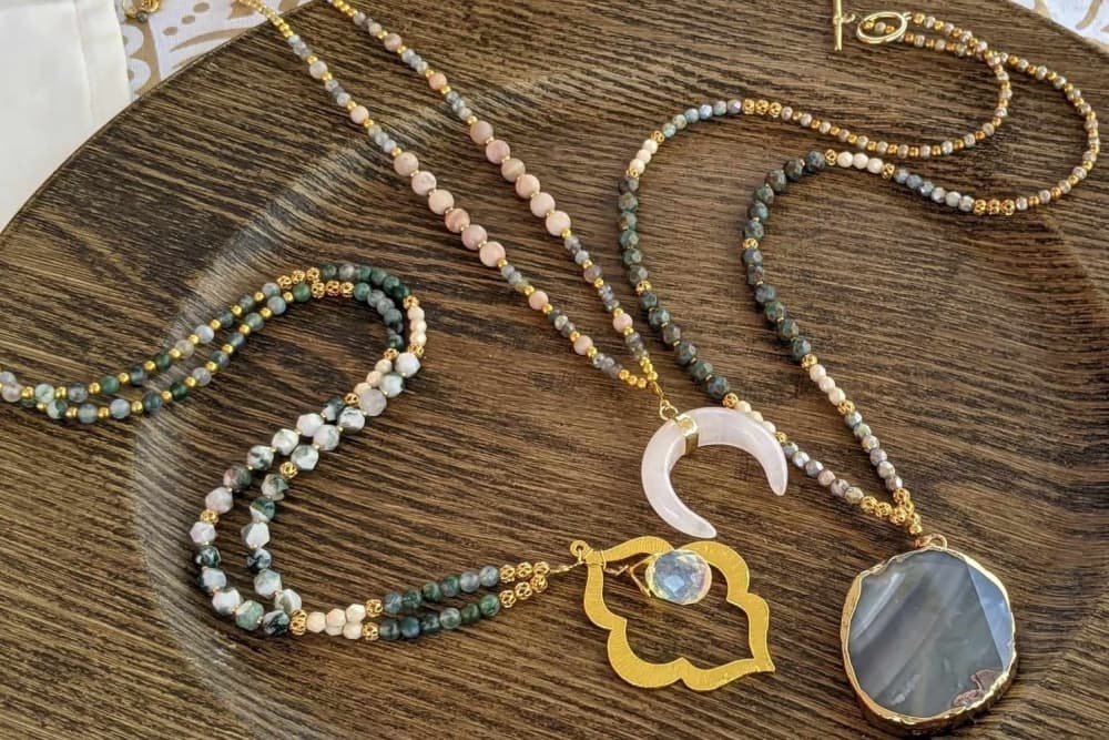 A wooden tray holds three necklaces.