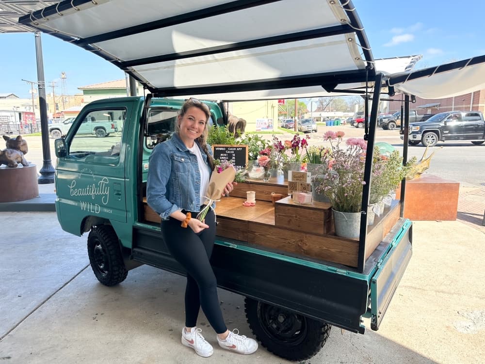 The owner smiles with a bouquet in front of the truck.