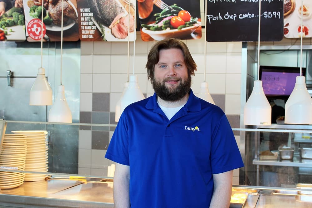 Man wearing Luby's shirt inside a Luby's restaurant. 