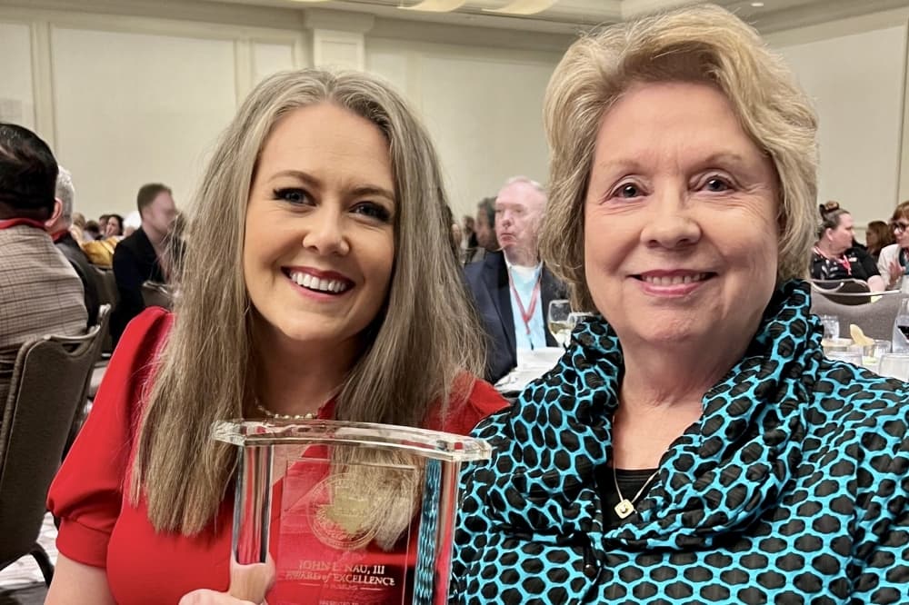 Two women pose with an award.